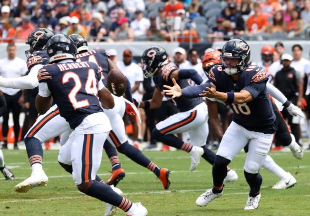 Bears quarterback Caleb Williams (18) tosses the ball to running back Khalil Herbert (24) in the first quarter against the Bengals in a preseason game at Soldier Field on Aug. 17, 2024, in Chicago. (John J. Kim/Chicago Tribune)