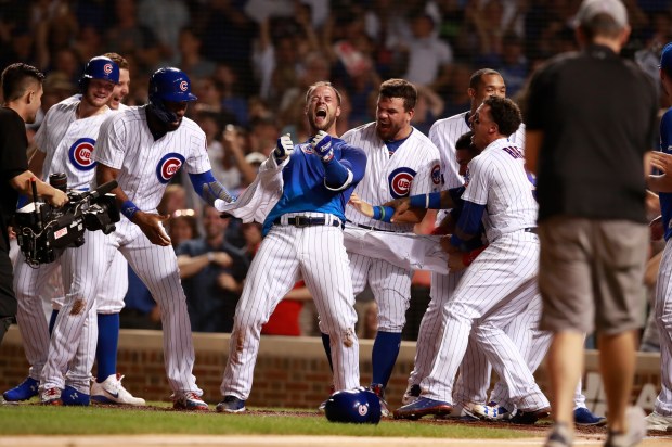 Cubs third baseman David Bote (13) celebrates with teammates after hitting a walk-off grand slam with two outs in the ninth inning against the Nationals on Aug. 12, 2018, at Wrigley Field. (Nuccio DiNuzzo/Chicago Tribune)