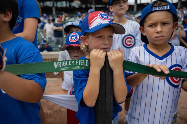 Ellis Foreman, 6, center, and brother Harrison Foreman, 8, right, of Logansport, Indiana, wait for autographs from Cubs players before the Cubs play against the Toronto Blue Jays at Wrigley Field in Chicago on Aug. 16, 2024. The Cubs won 6-5 against the Toronto Blue Jays. This was the boys' first Cubs game. (Tess Crowley/Chicago Tribune)