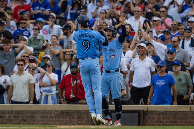 Toronto Blue Jays third base Ernie Clement (28) and Toronto Blue Jays left fielder Joey Loperfido (9) celebrate after scoring two runs in the ninth inning at Wrigley Field in Chicago on Aug. 16, 2024. The Cubs won 6-5 against the Toronto Blue Jays. (Tess Crowley/Chicago Tribune)