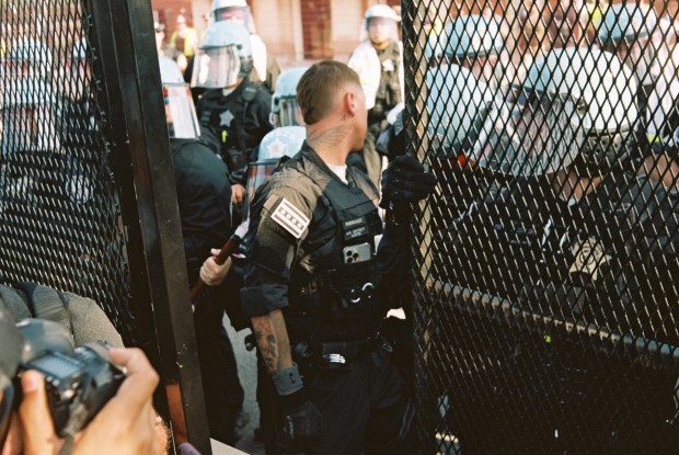 Officers attempt to put a fence together after it was crossed by activists in park #578 near the United Center during the first day of the Democratic National Convention on Aug. 19, 2024, in Chicago. (Armando L. Sanchez/Chicago Tribune)