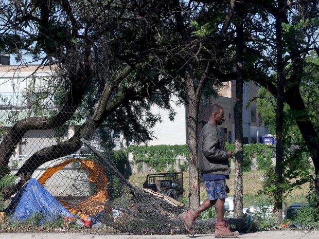 A man who later entered the camp passes by the the homeless encampment along South Desplaines Street and the Dan Ryan expressway, near Roosevelt Road in Chicago on July 15, 2024. The city cleared the homeless encampment days later. (Antonio Perez/Chicago Tribune)