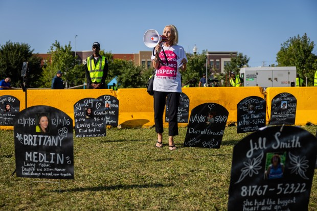 Lead Organizer of Moms United to End the War on Drugs Gretchen Burns Bergman, center, speaks with Trail of Truth, a substance abuse prevention coalition, in between signs that represent tombstones of people around the country that have died due to substance abuse at Park #578 in Chicago on Aug. 21, 2024. Bergmans' two sons died due to heroin overdoses. (Tess Crowley/Chicago Tribune)