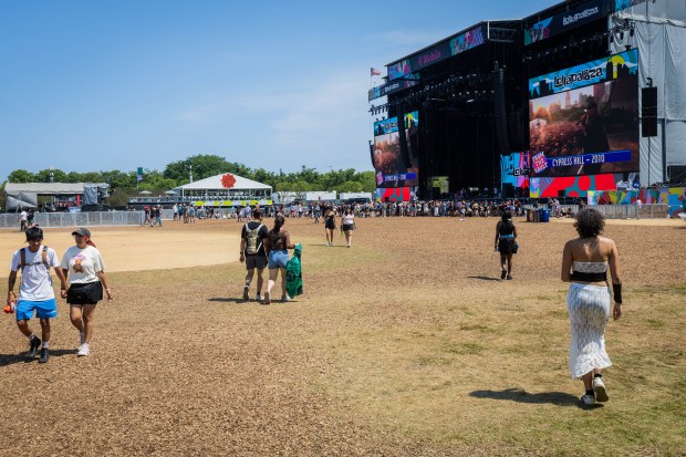 People walk on mulch used to prevent rain damage at Lower Hutchinson Field near the IHG Hotels & Resorts and T-Mobile stage during Lollapalooza in Chicago's Grant Park on Aug. 4, 2024. (Tess Crowley/Chicago Tribune)