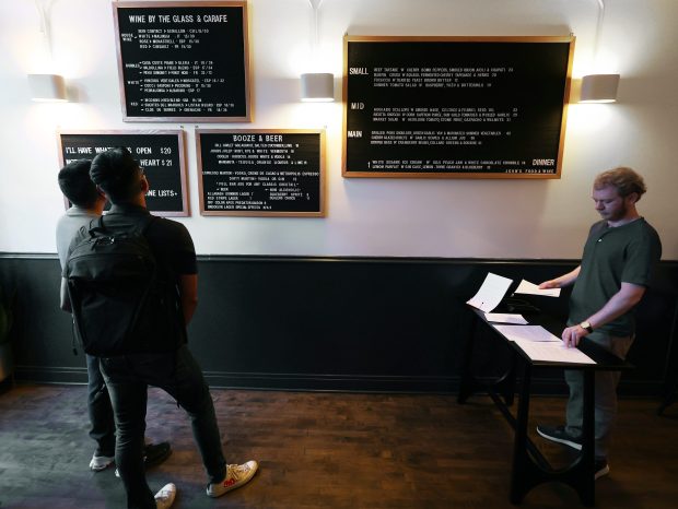 Customers study the wall-mounted menus before placing their orders at the table at right at John's Food and Wine in Lincoln Park. (Terrence Antonio James/Chicago Tribune)