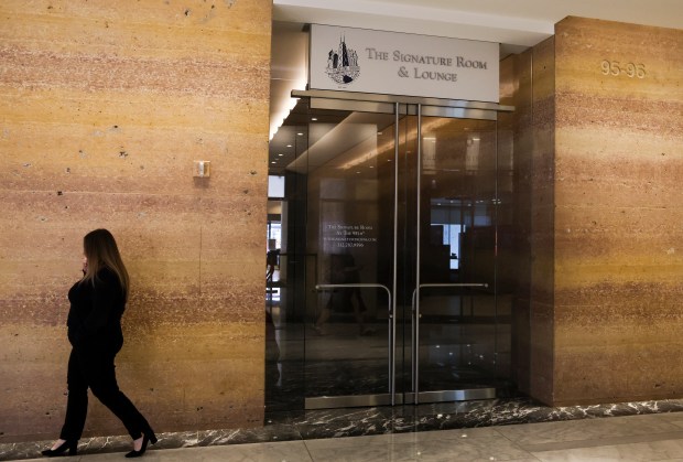 A person walks by signage for the Signature Room and Lounge inside a lobby of the 875 North Michigan Avenue building on May 30, 2024. (Eileen T. Meslar/Chicago Tribune)