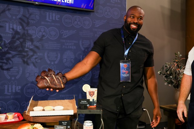 Former Chicago Bears defensive end and current suite holder Israel Idonije holds up the Bear Claw Pretzel, a new concession item, during a tasting event and hospitality exhibition at Soldier Field on Wednesday, Aug. 28, 2024.(Eileen T. Meslar/Chicago Tribune)