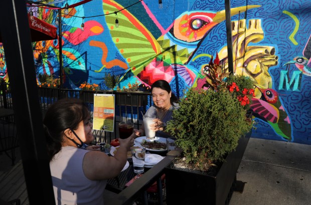 Outdoor diners Imelda Caballero and Guadalupe Cisneros click their glasses as the meal arrives at 5 Rabanitos restaurant at 18th St., in Chicago's Pilsen neighborhood, Nov. 5, 2020. (Antonio Perez/Chicago Tribune)