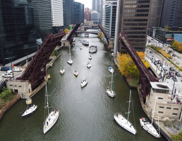 Sailboats travel south along the Chicago River through the lifted Van Buren Ave Bridge during the annual bridge lifts Oct. 25, 2023. (Trent Sprague/Chicago Tribune)