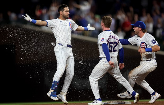 Chicago Cubs hitter Mike Tauchman celebrates with teammates Pete Crow-Armstrong (52) and Nico Hoerner (2) after Tauchman drove in the game-winning run on a walk-off double in the ninth inning of a game against the St. Louis Cardinals at Wrigley Field in Chicago on Aug. 1, 2024. (Chris Sweda/Chicago Tribune)