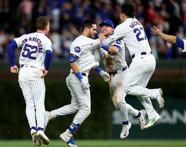 Chicago Cubs hitter Mike Tauchman celebrates with teammates Pete Crow-Armstrong (52), Nico Hoerner (2), and Seiya Suzuki (27), after Tauchman drove in the game-winning run on a walk-off double in the ninth inning of a game against the St. Louis Cardinals at Wrigley Field in Chicago on Aug. 1, 2024. (Chris Sweda/Chicago Tribune)