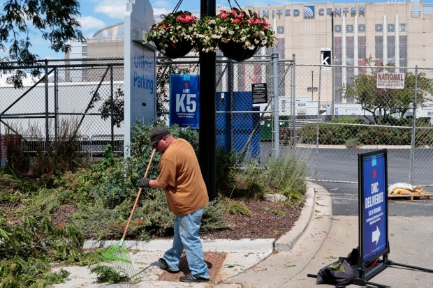 With the United Center behind him, a worker from the Department of Streets and Sanitation rakes debris along Adams Street near Damen Avenue as crews finish cleanup projects on Aug. 9, 2024, ahead of the upcoming Democratic National Convention. (Antonio Perez/Chicago Tribune)