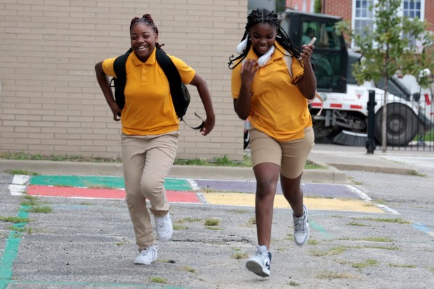 Students Lyric Taylor, left, and Alexis West, both seventh graders run towards a fellow student as they arrive on their first day back to school at Chalmers Elementary Specialty School in Chicago, Monday, Aug. 26, 2024. (Antonio Perez/Chicago Tribune)