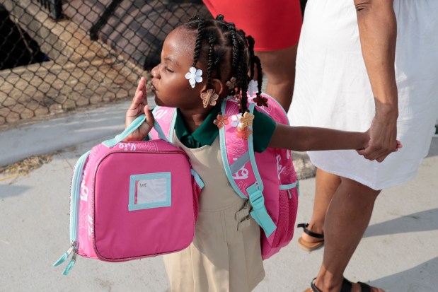 A student throws a kiss as she is lead into the school on their first day back to school at Chalmers Elementary Specialty School on Monday, Aug. 26, 2024. (Antonio Perez/Chicago Tribune)