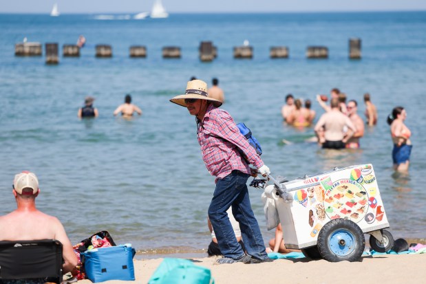 Paletero Gonzalo Garcia walks on North Avenue Beach selling ice cream on Monday, Aug. 26, 2024. People filled the beaches around the city as the National Weather Service issued an excessive heat warning from Monday afternoon to Tuesday evening. (Eileen T. Meslar/Chicago Tribune)