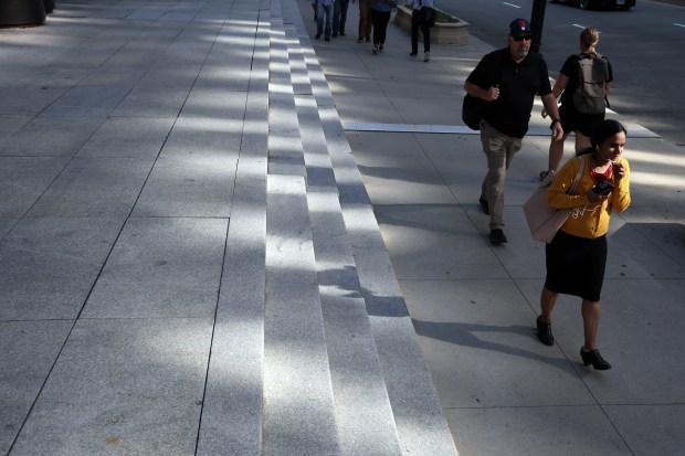 Reflected afternoon sunlight splashes onto pedestrians and steps on Wacker Drive near Adams Street in Chicago on Monday, Aug. 26, 2024, with the temperature hovering near 100 degrees. (Terrence Antonio James/Chicago Tribune)