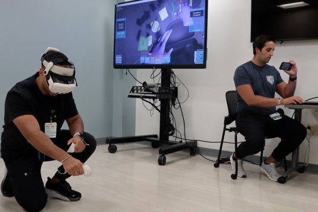 Resident physician Abdul-Rahman Saleh takes part in a virtual reality training, simulating a mass casualty event, at Rush University Medical Center in Chicago, Wednesday, July 24, 2024. At right is Dr. Nick Cozzi, of Rush University, on laptop. The participants would arrive at a scene in virtual reality, access the situation and perform triage on the virtual reality victims. Rush University Medical Center has been working with Ohio State University's department of emergency medicine on preparedness using virtual reality. (Antonio Perez/Chicago Tribune)