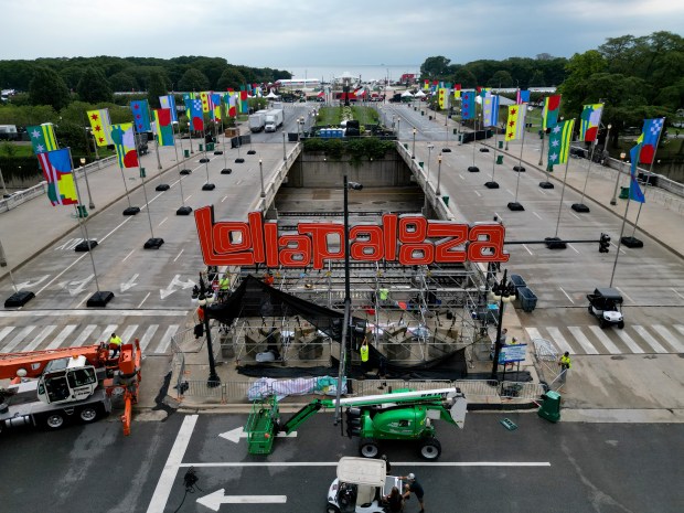 Workers remove protective mesh from scaffolding as they prepare to remove the gigantic red Lollapalooza sign along East Ida B. Wells Drive and East Congress Plaza Drive on Aug. 5, 2024, in Chicago. (Stacey Wescott/Chicago Tribune)