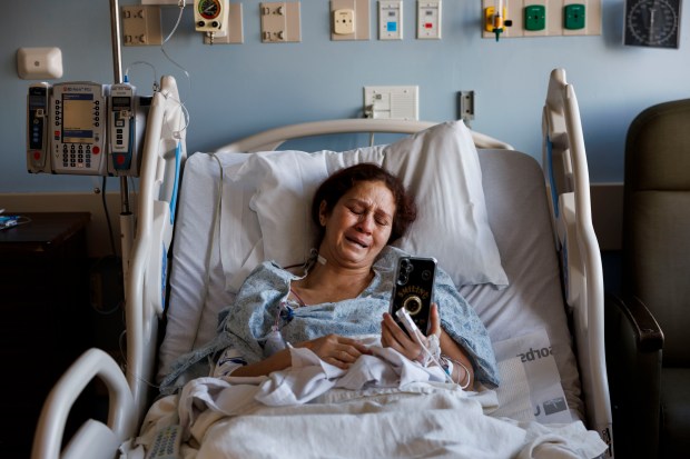 Esperanza Mendez cries while talking with her mother in Venezuela as she lays in a bed at Stroger Hospital after having her lipoma surgically removed on Jan. 29, 2024. Mendez was unable to receive proper attention for the lump in her neck in Venezuela, where she also struggled to make enough money to feed her family. (Armando L. Sanchez/Chicago Tribune)