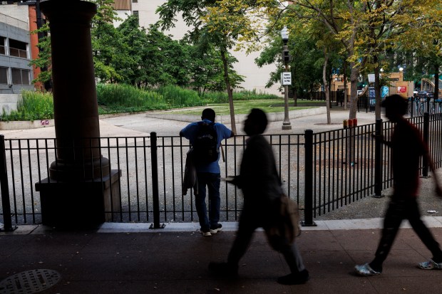 A fence surrounds an empty Pritzker Park near the Standard Club migrant shelter on Aug. 1, 2024, in Chicago. Migrants staying at the shelter said a few weeks ago officials put up a fence where dozens of shelter residents typically gathered daily to sell cigarettes or stand in a pack. The city said it was not involved in putting up that fence. (Armando L. Sanchez/Chicago Tribune)