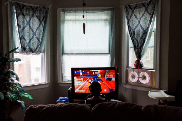 Pedro Mendez, 10, plays video games in his home on July 9, 2024. Esperanza didn't feel comfortable letting her kids play outside in Englewood, so Pedro and his sister Yuledy spend most of their time indoors. (Armando L. Sanchez/Chicago Tribune)