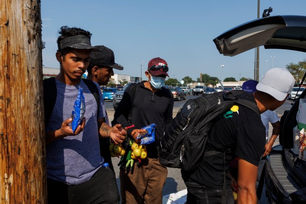 Migrants are given food while attempting to get work in the Home Depot parking lot along West 87th Street on Aug. 8, 2024, in Chicago. Earlier in the week a migrant was shot by a security guard in a parking lot near the Home Depot. (Armando L. Sanchez/Chicago Tribune)