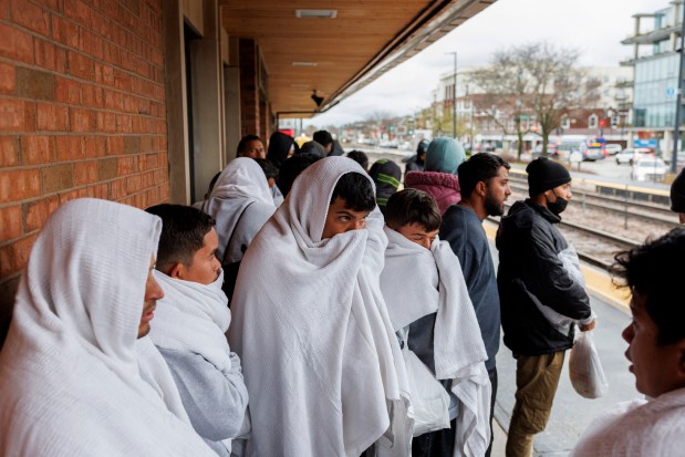 Migrants wait at a Metra stop after traveling by bus from El Paso, Texas Wednesday, April 3, 2024, in Wilmette. Migrants on the bus said the ride took almost 30 hours. (Armando L. Sanchez/Chicago Tribune)