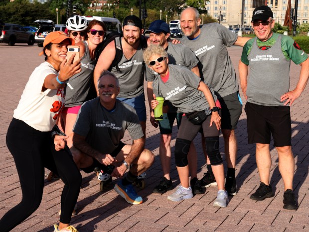 A passer-by gets a group photo with the runners on Aug. 20, 2024.(Antonio Perez/Chicago Tribune)