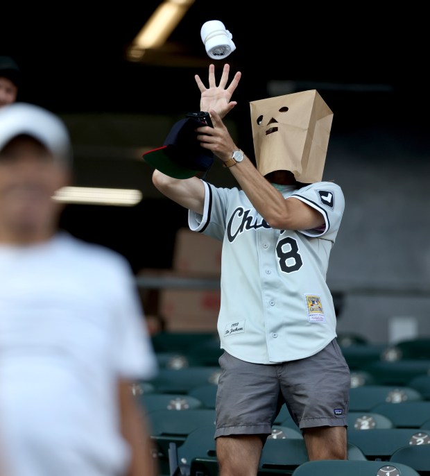 A White Sox fan wearing a bag over his head catches a free T-shirt during the seventh inning of a game against the Rangers on Aug. 28, 2024, at Guaranteed Rate. (Chris Sweda/Chicago Tribune)