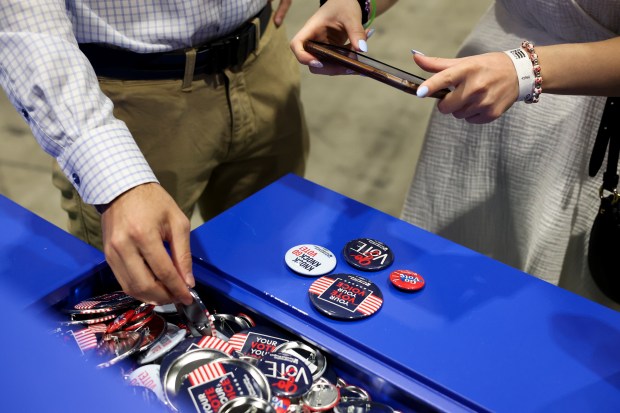 Sam Schwartz and Emma Levine take photos of buttons while they check out booths at the DemPalooza at McCormick Place Convention Center on Aug. 19, 2024. (Eileen T. Meslar/Chicago Tribune)