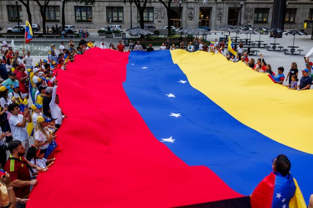 Venezuelans and supporters gather around a large flag in Daley Plaza to protest President Nicolás Maduro after last Sunday's election, Aug. 6, 2024. (Armando L. Sanchez/Chicago Tribune)