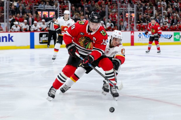 Blackhawks center Jonathan Toews and Flames left wing Johnny Gaudreau chase after the puck on Jan. 7, 2019, at the United Center. (Armando L. Sanchez/Chicago Tribune)