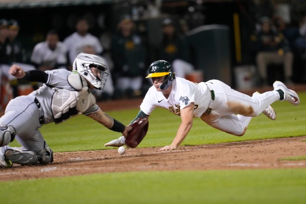 Oakland Athletics' Zack Gelof, right, slides home to score against Chicago White Sox catcher Korey Lee during the eighth inning of a baseball game in Oakland, Calif., Monday, Aug. 5, 2024. (AP Photo/Jeff Chiu)