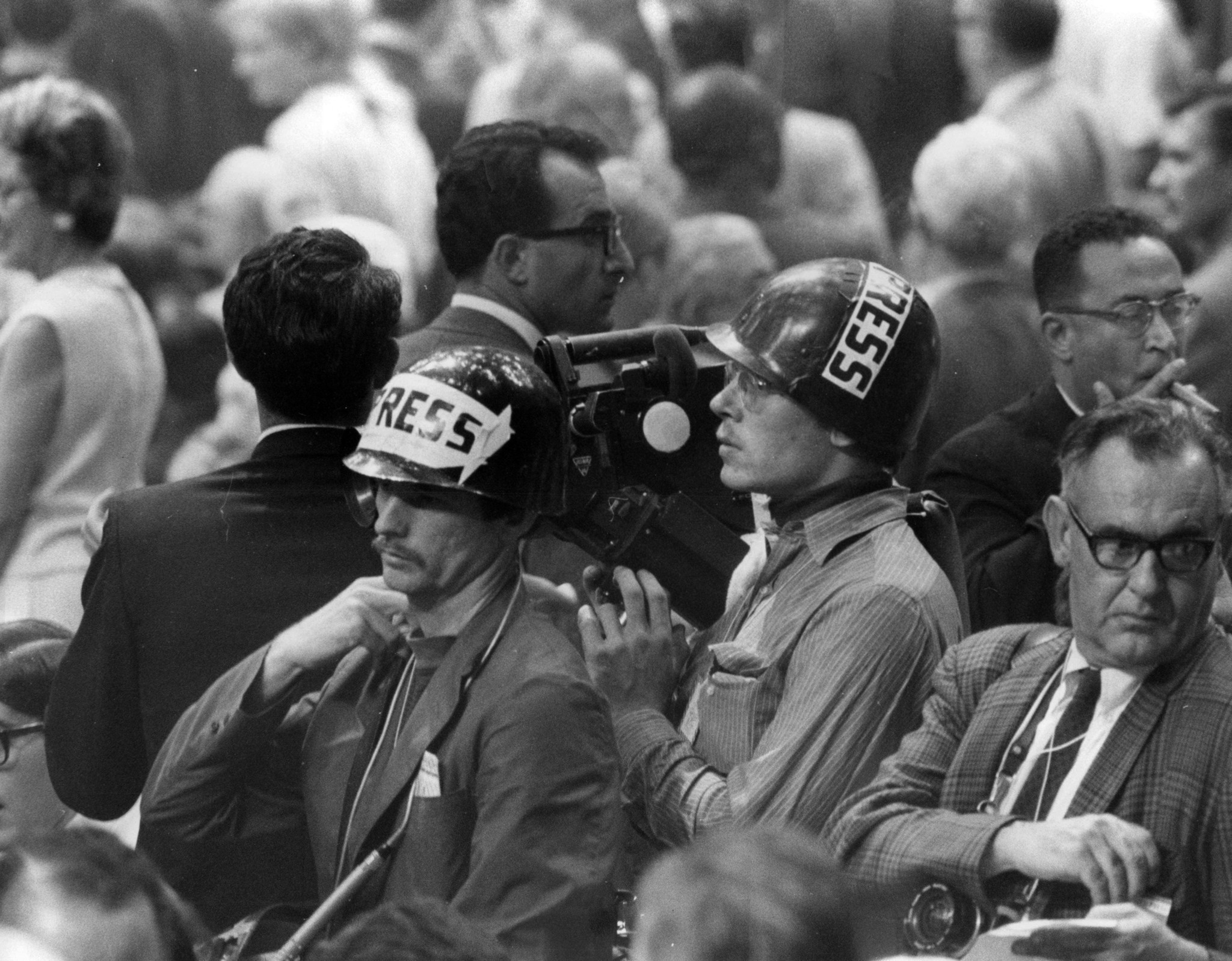 A TV crew, wearing helmets, on the convention floor at...