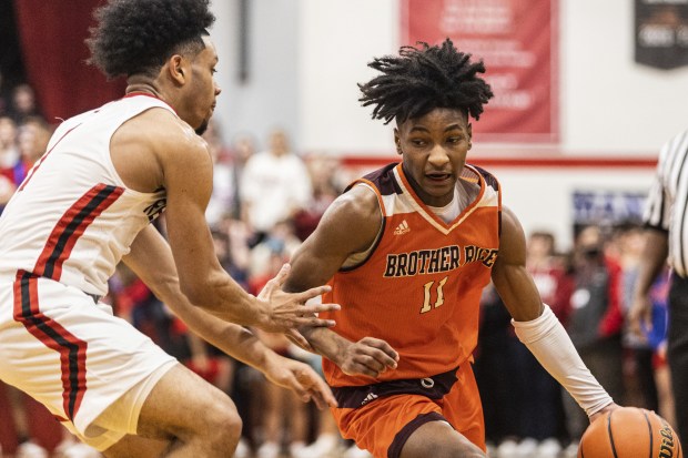 Brother Rice's Ahmad Henderson (11) drives to the lane as Marist's Mason Ross (1) defends during a nonconference game in Chicago on Tuesday, Jan. 17, 2023.