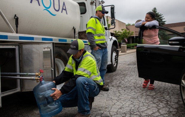 Davida Colquitt of University Park waits as workers from Aqua Illinois fill containers with drinking water at the Community Center in 2019. (Zbigniew Bzdak / Chicago Tribune)