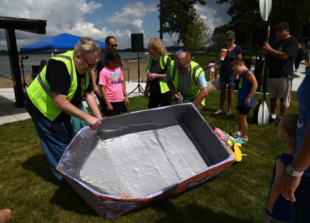 Fifth from left, Jeff Fraas of Fox Lake, boat inspector and official race timer for the Cardboard Race Committee, inspects a boat before launching at the Cardboard Boat Race on Aug. 17, 2024 at Lakefront Park in Fox Lake. (Karie Angell Luc/Lake County News-Sun)