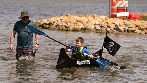 Riding in The Black Pearl is Ryan Ludden, 9, a fourth-grader from Fox Lake. Ryan's parent John Ludden is in the water at the Cardboard Boat Race on Aug. 17, 2024 at Lakefront Park in Fox Lake. (Karie Angell Luc/Lake County News-Sun)