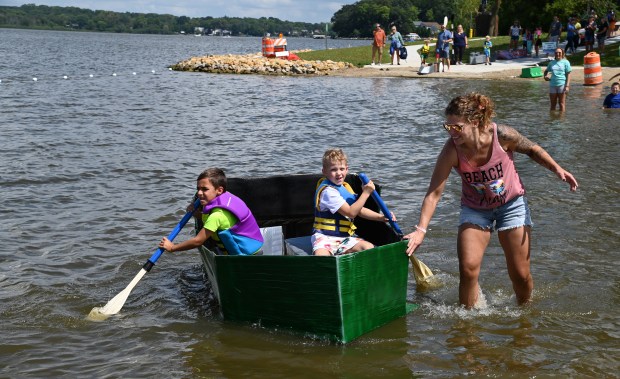 Rowing on the boat the Pirate Flames are, from left, Jayce Sereyka, 6, a first-grader of Fox Lake and KJ McCollor, 6, a first-grader from Spring Grove making their way to the finish line buoy. In the water is KJ's parent Kayla McCollor at the Cardboard Boat Race on Aug. 17, 2024 at Lakefront Park in Fox Lake. (Karie Angell Luc/Lake County News-Sun)