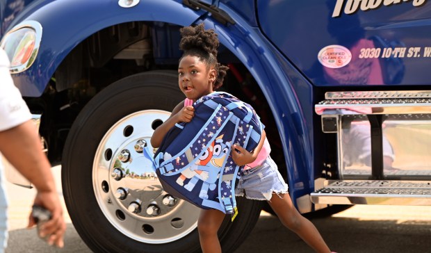 Bethanie Jackson, 6, a rising first-grader from Gurnee is given a new backpack filled with school supplies from donor and parade participant Unique Towing of Waukegan at the North Chicago Community Days Parade on Aug. 3, 2024 in North Chicago. (Karie Angell Luc/Lake County News-Sun)