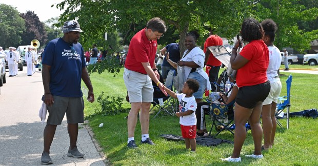 In red shirt, U.S. Rep. Brad Schneider (D-10th) of Highland Park says hello with a high five gesture to Dhamir Walker, 2, of North Chicago at the North Chicago Community Days Parade on Aug. 3, 2024 in North Chicago.