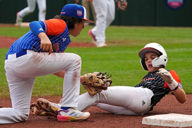 Hinsdale, Ill.'s Collin Boots, left, tags out Staten Island, N.Y.'s Dean Scarangello at third base to end the fourth inning of a baseball game at the Little League World Series in South Williamsport, Pa., Sunday, Aug. 18, 2024. (AP Photo/Gene J. Puskar)