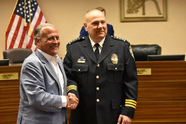 Mayor Gary Grasso welcomes incoming Police Chief Marc Loftus to the job of police chief Monday at the Burr Ridge Village Board meeting. (Jesse Wright for the Pioneer Press)