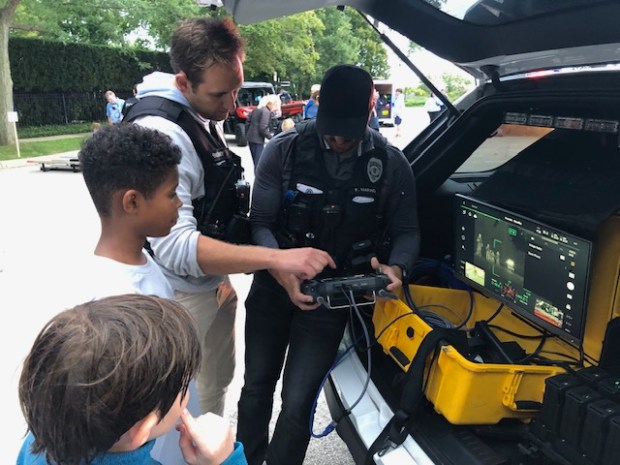 Detective Ryan McEnerney (left) and Officer Fil Marino demonstrate how to operate a drone to two children. (Daniel I. Dorfman)