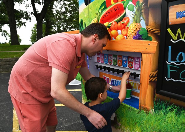 Sebastian Czubacki, 3, of Port Barrington, selects flavors for his Kona Ice treat with the help of his father Kamil Czubacki at the Food Truck Social event at Paulus Park in Lake Zurich on July 24, 2024. (Karie Angell Luc/Pioneer Press)