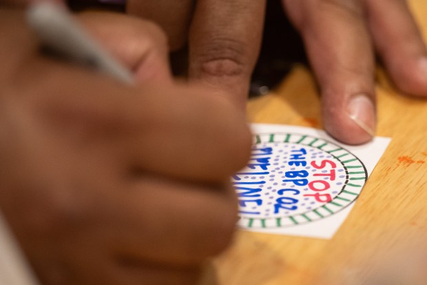 Artist William Estrada decorates a protest button during a community conversation at the Hammond Public Library on the proposed BP CO2 pipeline on Wednesday, Aug. 21, 2024. (Kyle Telechan/for the Post-Tribune)