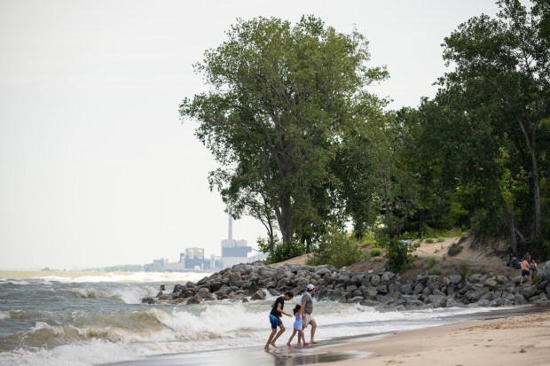 Visitors walk along the shore of Lake Michigan at Beverly Shores on Wednesday, Aug. 7, 2024, amidst search efforts for a Minnesota teen that was lost in the waves the previous day. (Kyle Telechan/for the Post-Tribune)