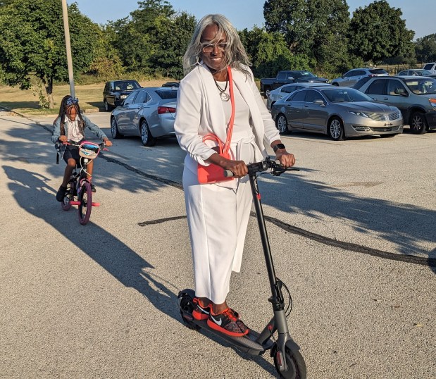 Williams Elementary Principal Linda Golston is followed by a student as she rides her motorized scooter to school Wednesday. (Carole Carlson/Post-Tribune)