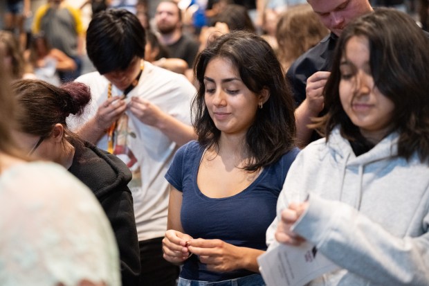 Incoming Indiana University Northwest students unwrap and affix their Indiana University pins during the school's induction ceremony on Tuesday, Aug. 27, 2024. (Kyle Telechan/for the Post-Tribune)