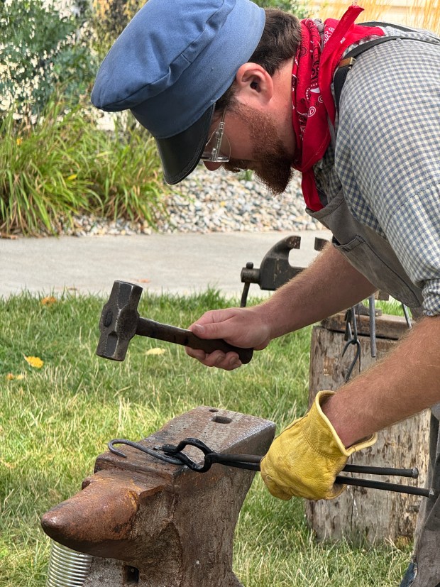 Blacksmith Solomon Burgo, of Fish Lake, hammers a pot hook into shape after heating it in his portable forge. (Doug Ross/Post-Tribune)